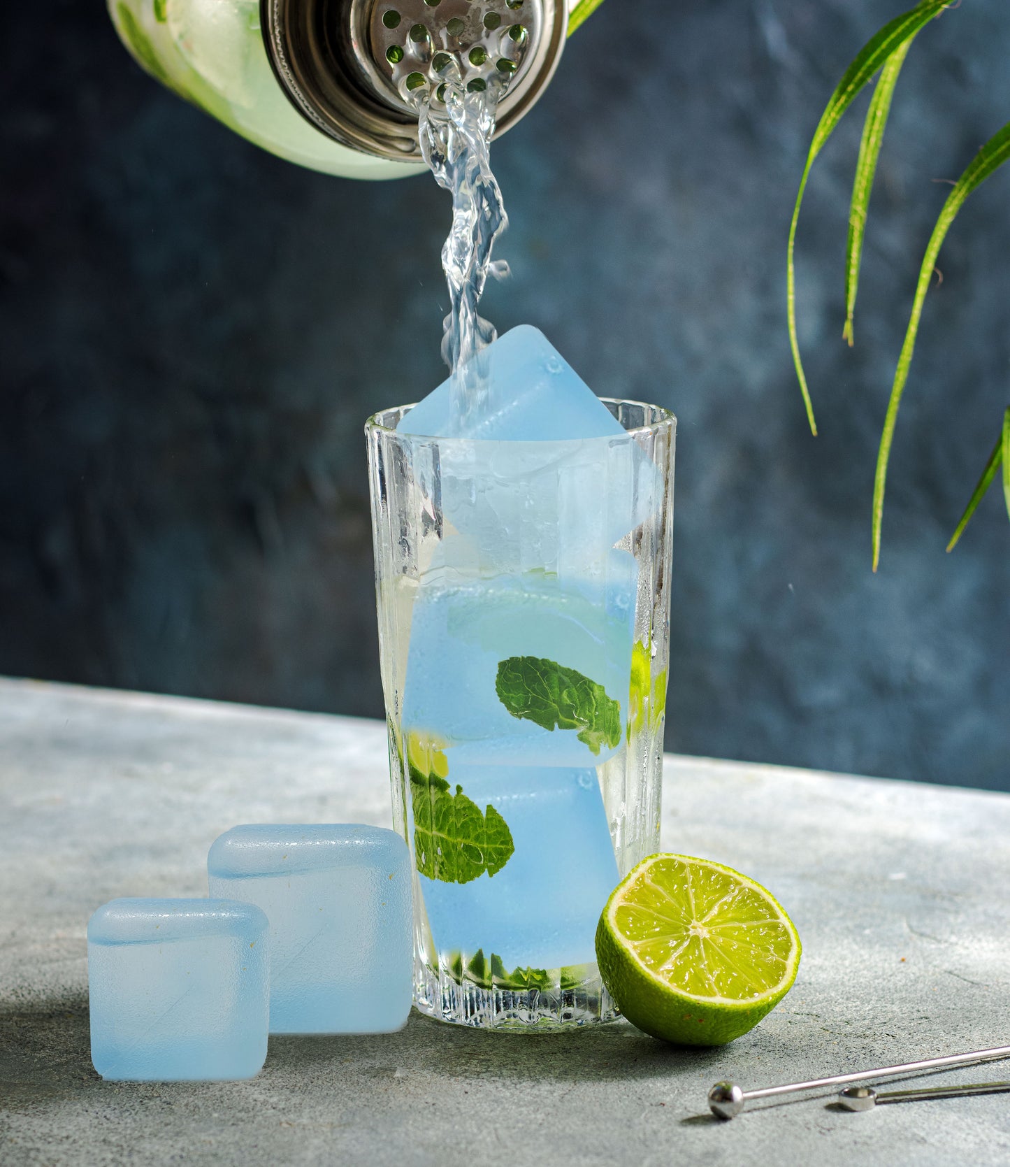 Reusacube reusable ice cubes chilling a drink as liquid is poured over mint and lime