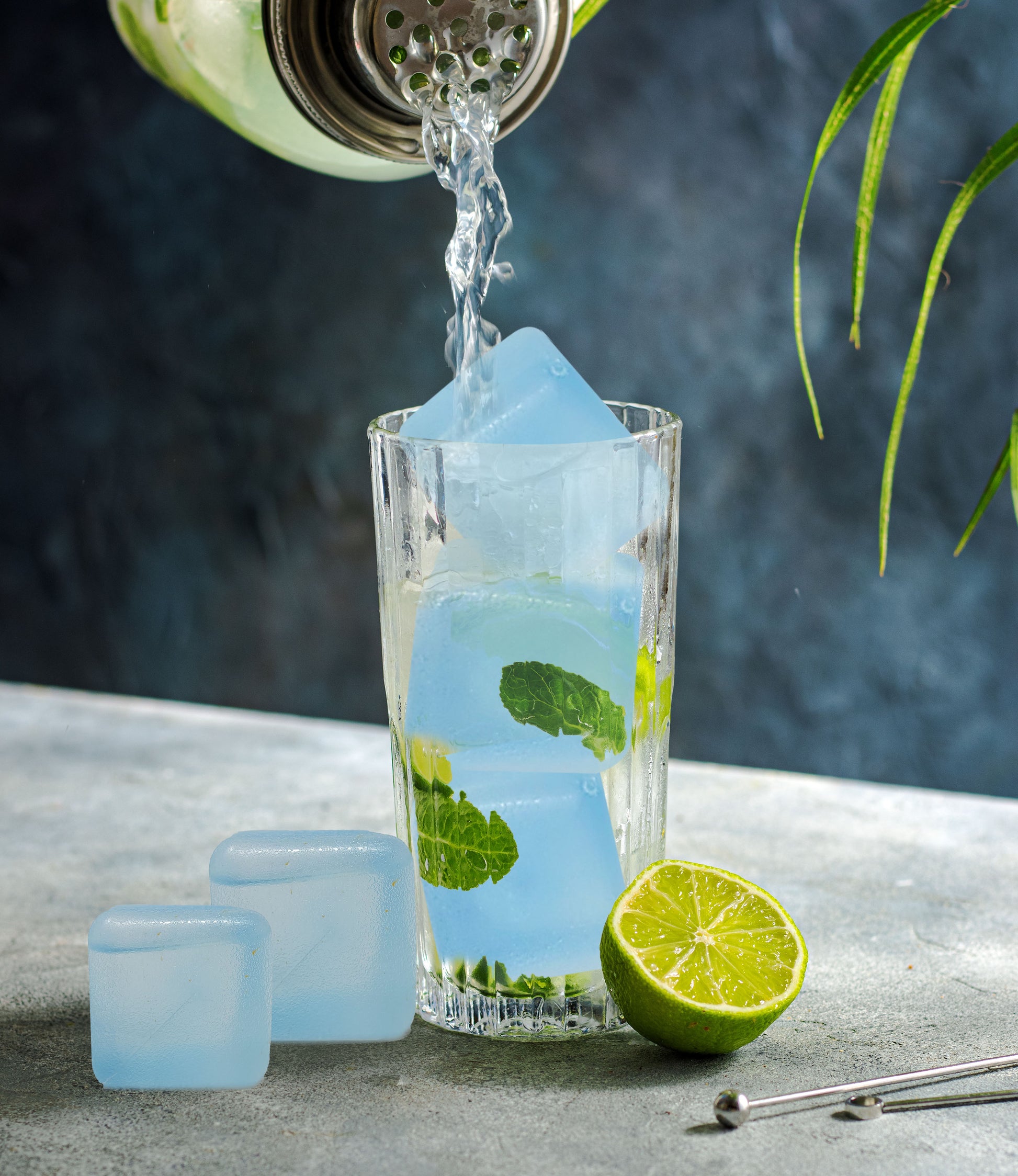Reusacube reusable ice cubes chilling a drink as liquid is poured over mint and lime