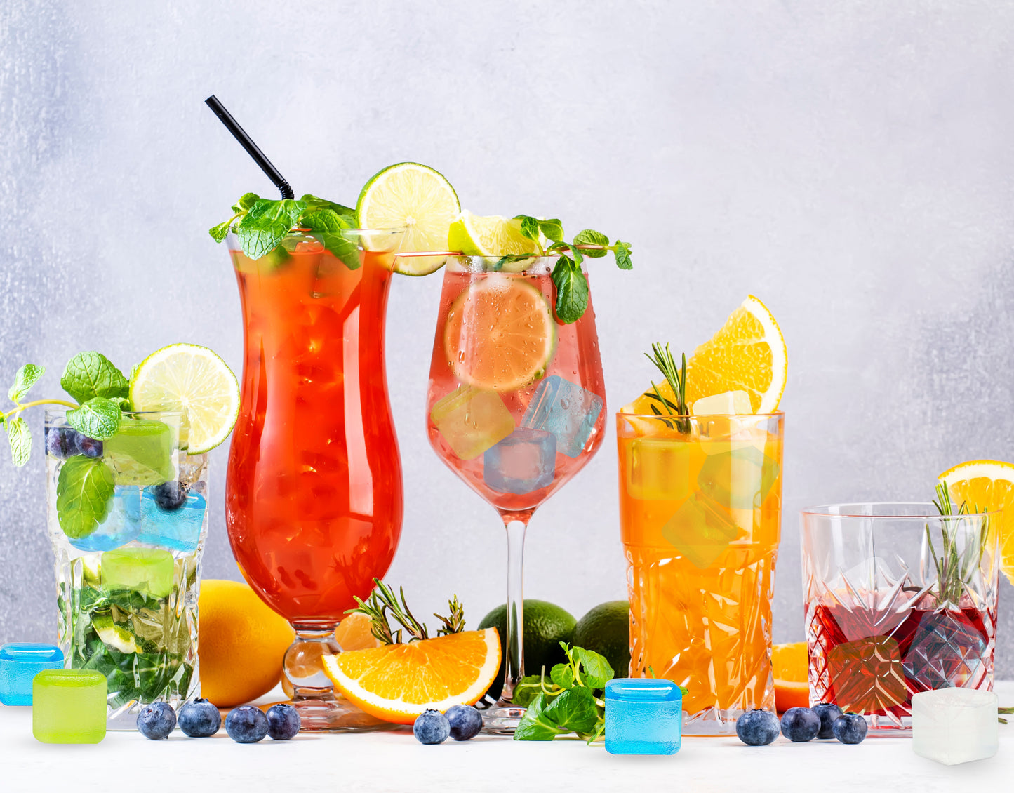Reusable ice cubes chilling assorted cocktails with fruit and herb garnishes